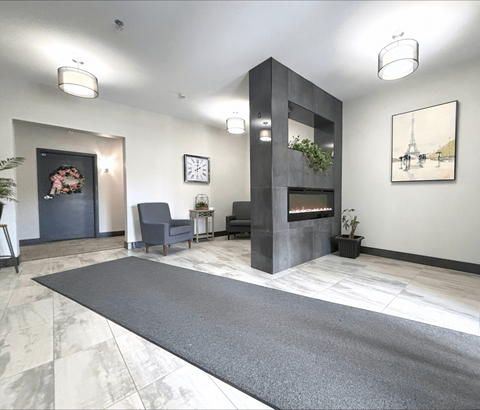 A modern living room with a grey rug and a fireplace.