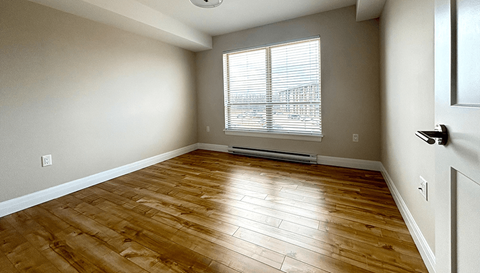 an empty living room with wood floors and a window