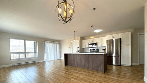 an open kitchen and living room with a wood floor