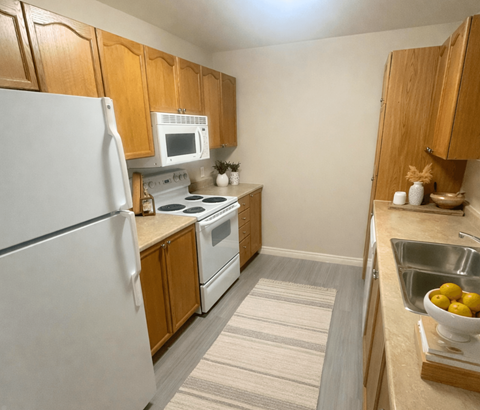 A kitchen with a white refrigerator, white stove, and wooden cabinets.