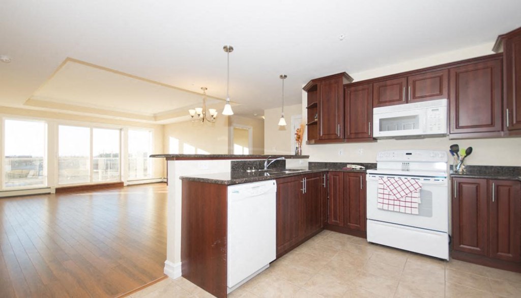 A kitchen with white appliances and dark wood cabinets.