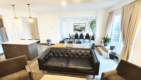 A black leather couch is in the center of a well-decorated living room.