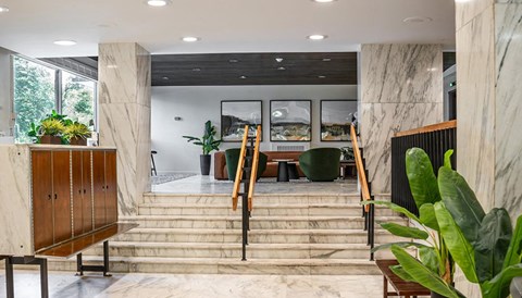 the lobby of a building with stairs and chairs