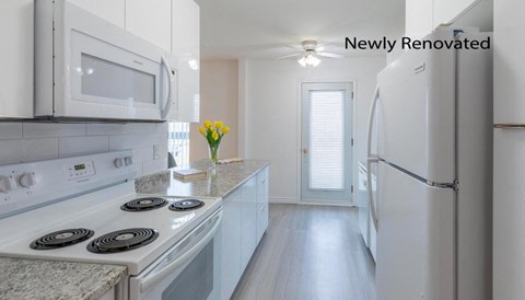 A newly renovated kitchen with white appliances and a marble countertop.