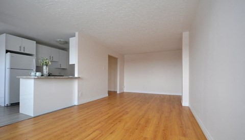 A kitchen with white cabinets and a wooden floor.