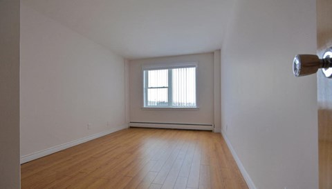 A room with wooden flooring and a window with blinds.