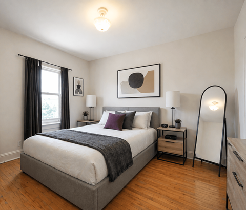 A bedroom with a large bed and a wooden floor.