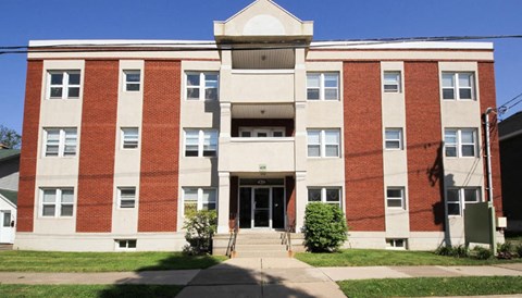 A red brick building with a white trim and a green sign on the front.