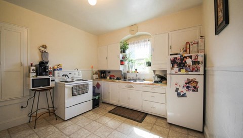 A kitchen with white appliances and a refrigerator covered in magnets.