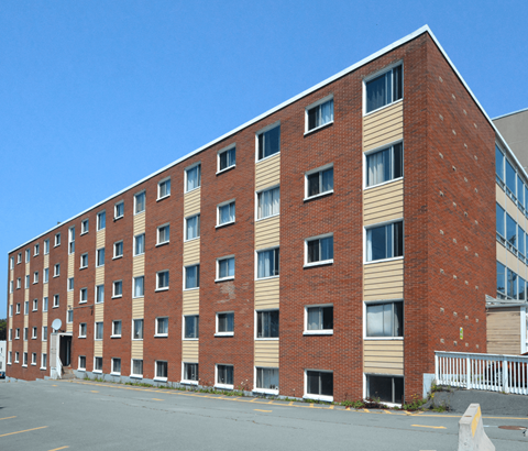 A red brick building with a parking lot in front.