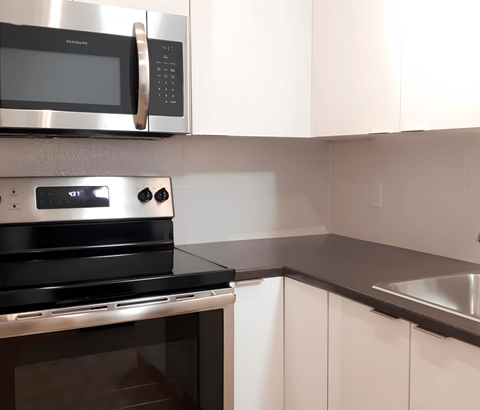 A modern kitchen with a stainless steel oven and microwave above a black stove.
