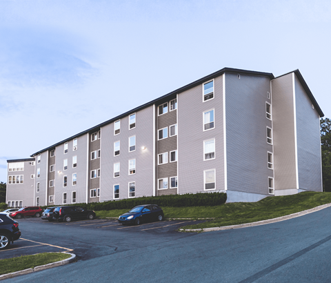 A large apartment building with a parking lot in front.