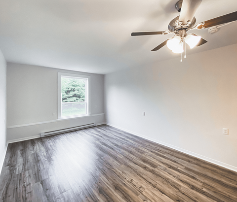 A room with a ceiling fan and wooden flooring.