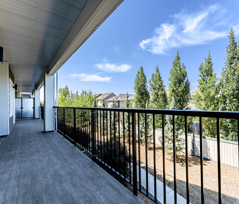 A balcony with a black railing and a view of trees and houses.