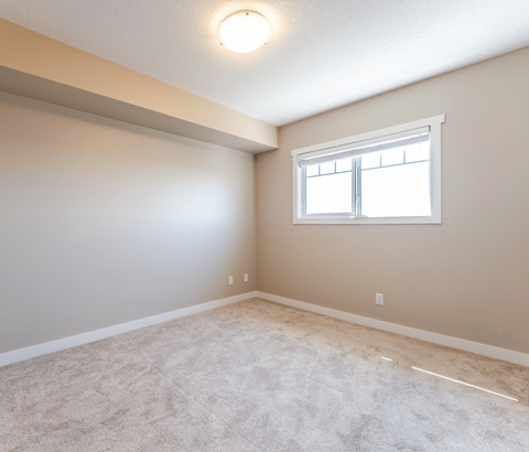 A room with a window and carpeted floor.