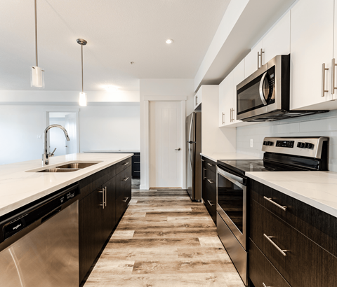 A modern kitchen with dark wood cabinets and stainless steel appliances.