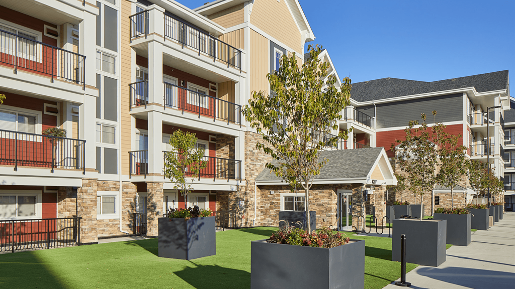 an exterior view of an apartment building with green grass and trees