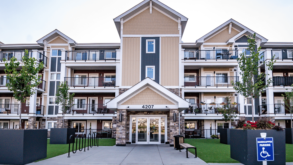 an exterior view of an apartment building with a driveway and a wheelchair ramp