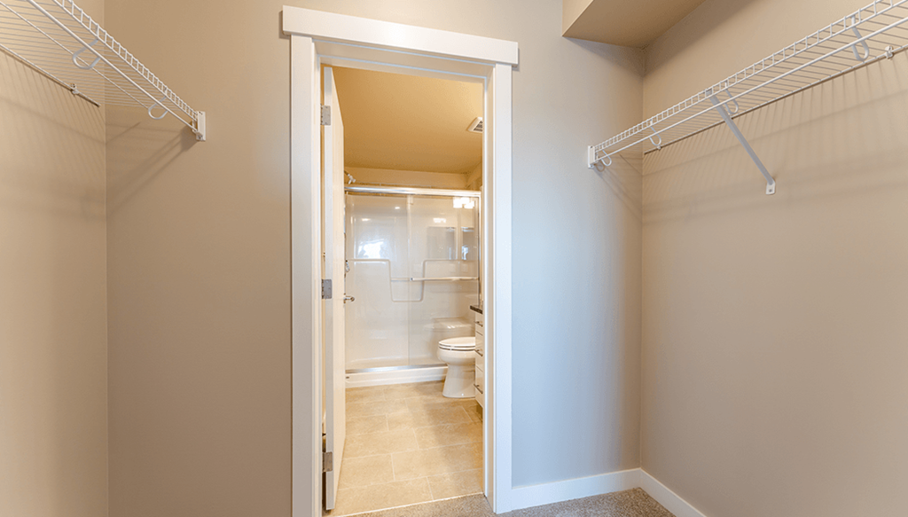 A white hallway with a doorway leading to a bathroom.