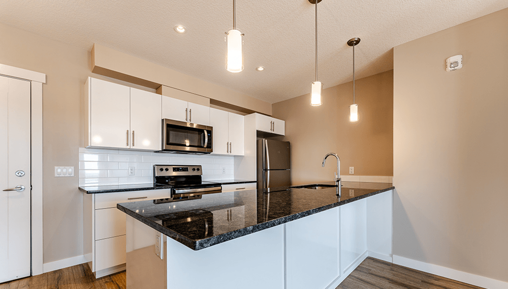A kitchen with a black countertop and white cabinets.