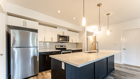 A modern kitchen with a stainless steel refrigerator and black cabinets.