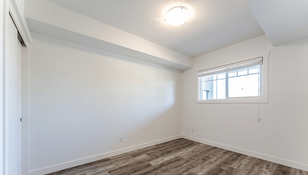 A room with a window and wooden flooring.