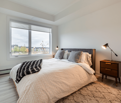 A bedroom with a large bed and a window overlooking a cityscape.