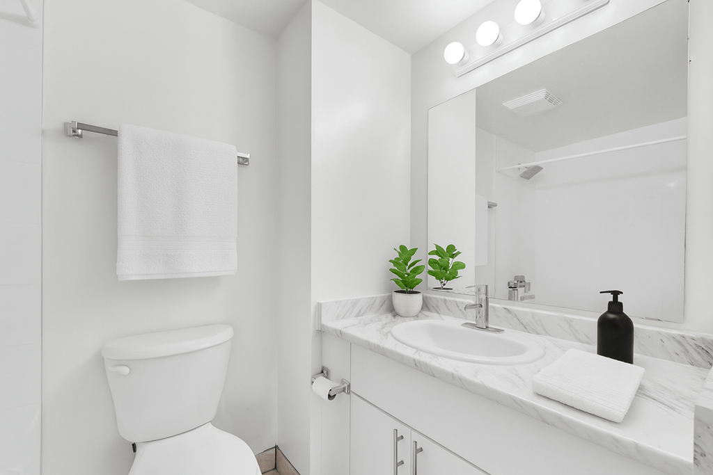 A white bathroom with a toilet, sink, and mirror.