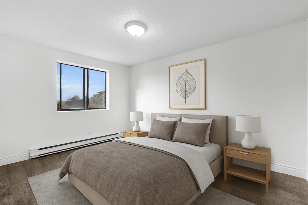 A bedroom with a large bed and a window overlooking a tree.