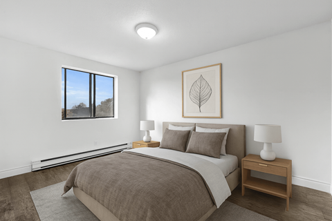 A bedroom with a large bed and a window overlooking a tree.