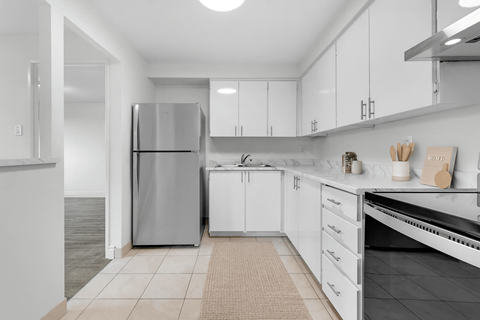 A modern kitchen with white cabinets and a stainless steel refrigerator.