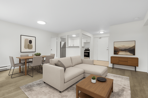 A modern living room with a white sofa, a wooden coffee table, and a dining table with chairs.