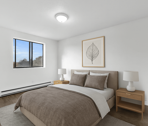 A bedroom with a large bed and a framed leaf picture on the wall.