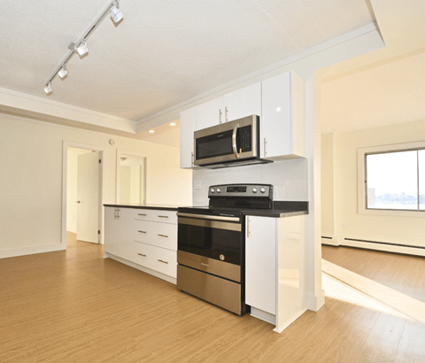 A modern kitchen with white cabinets and stainless steel appliances.
