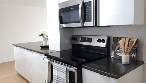 A modern kitchen with a black countertop and white cabinets.