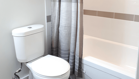 A white toilet sits next to a bathtub in a bathroom.