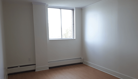A room with a window and a wall-mounted air conditioner.