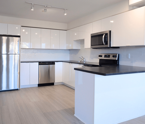 A modern kitchen with white cabinets and a black countertop.