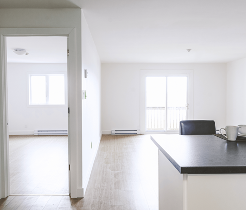 A black countertop with a white fridge and a black chair in the middle of the room.