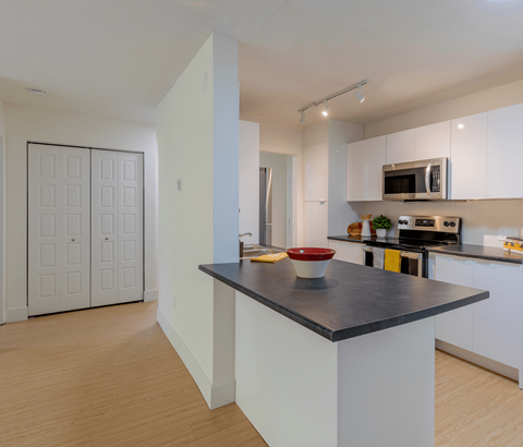 A kitchen with a black countertop and white cabinets.
