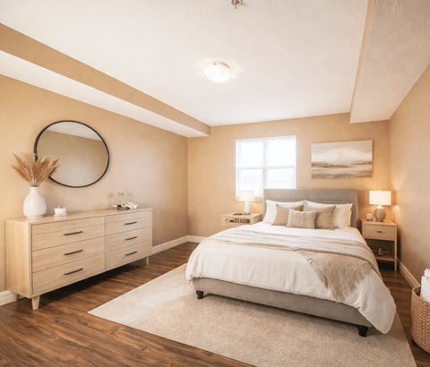 A bedroom with a large bed, a dresser, and a mirror on the wall.