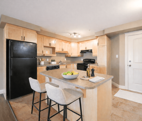 A kitchen with a black fridge, white chairs, and a marble countertop.
