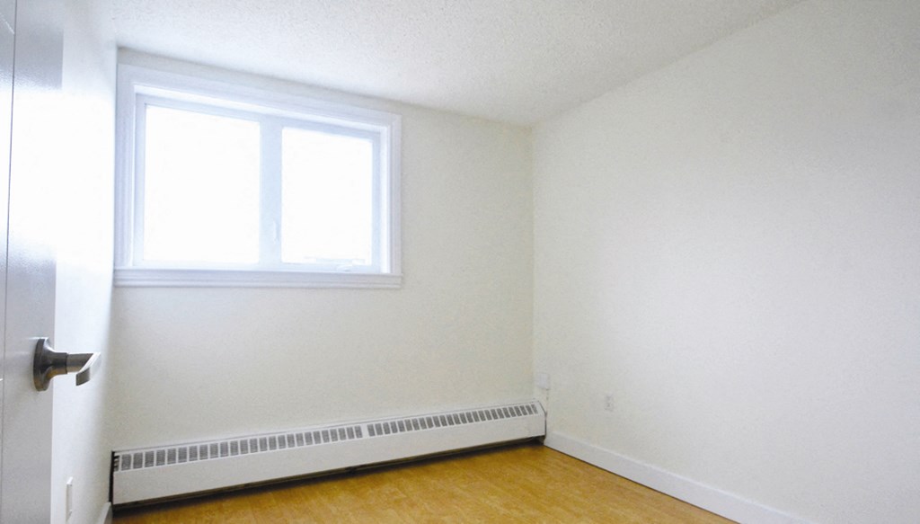 an empty room with a window and a wood floor