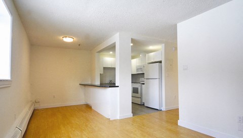 an empty living room and kitchen with a wood floor