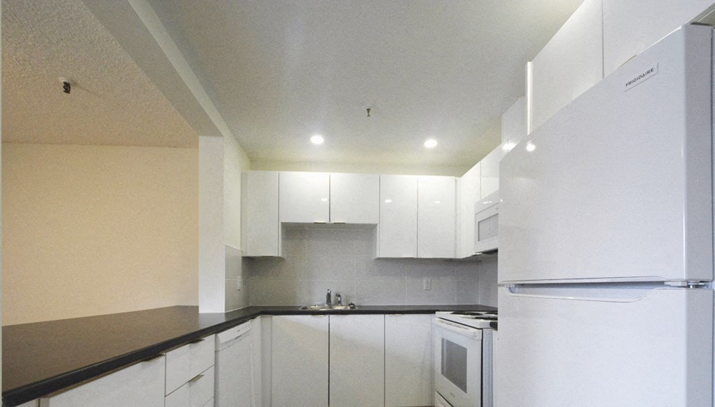 an empty kitchen with white appliances and white cabinets