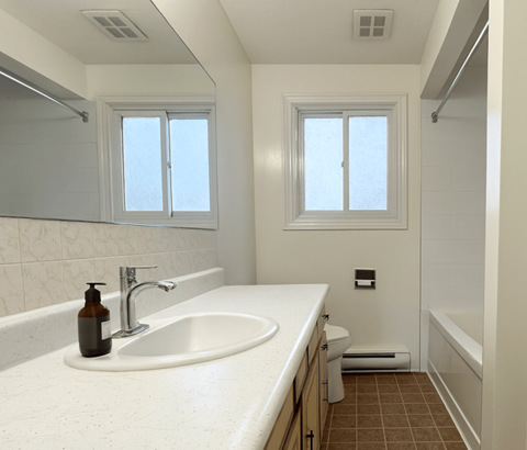 A bathroom with a white sink and brown tiles.