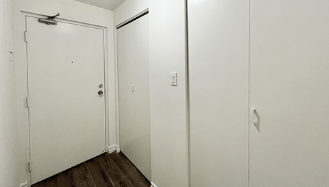 A white door with a silver handle is in a room with a white wall and a white door.