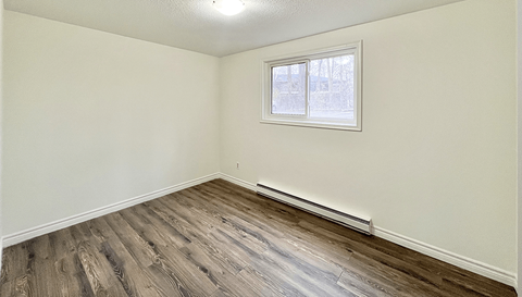 A room with a window and wooden flooring.