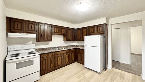 A kitchen with white appliances and brown cabinets.