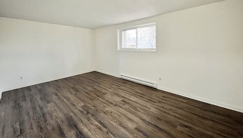 A room with a window and wooden flooring.